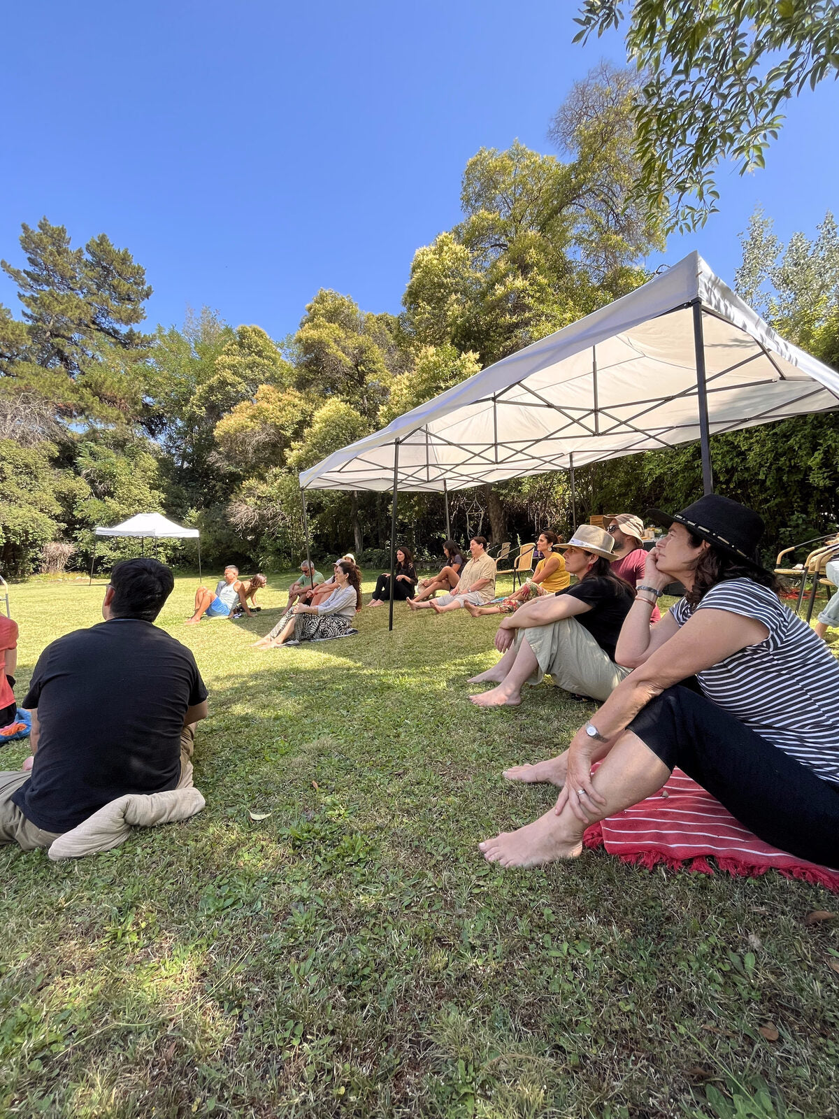 Jardín en El Arrayán con toldos y personas descalzas sobre el pasto